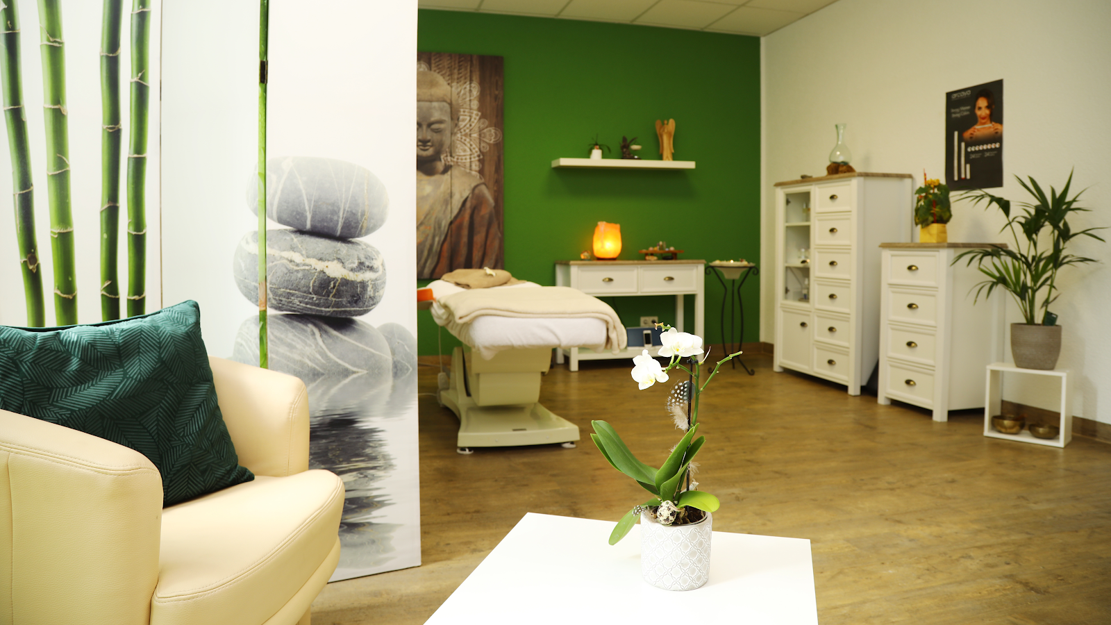 Behandlungsraum von CosVital mit grüner Akzentwand und Buddha-Kunstwerk